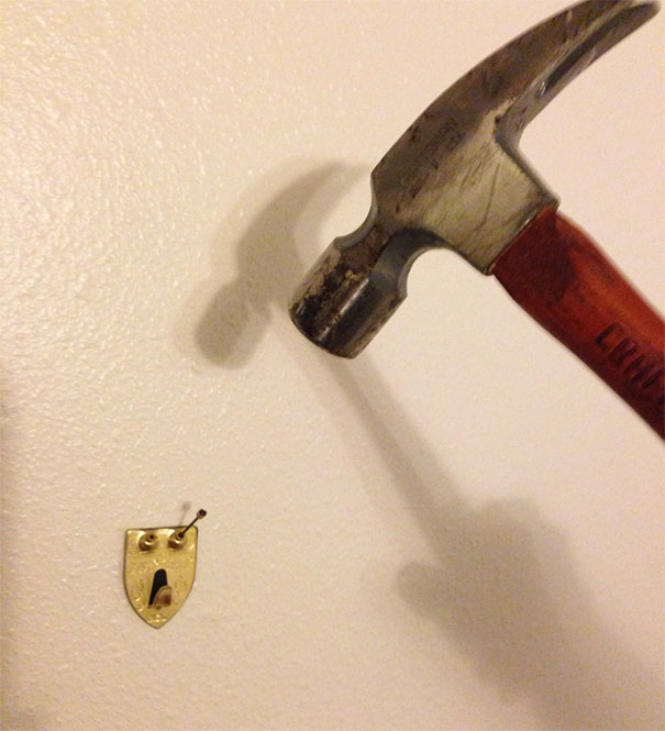 Hammer casting a shadow resembling a face next to a wall hook creating a funny pareidolia example in everyday objects.