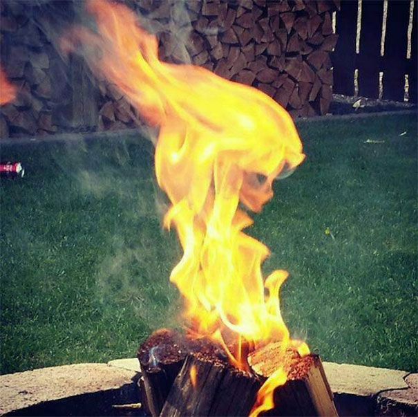 Flame shaped like a human face over burning logs, showcasing a funny example of pareidolia in everyday objects.