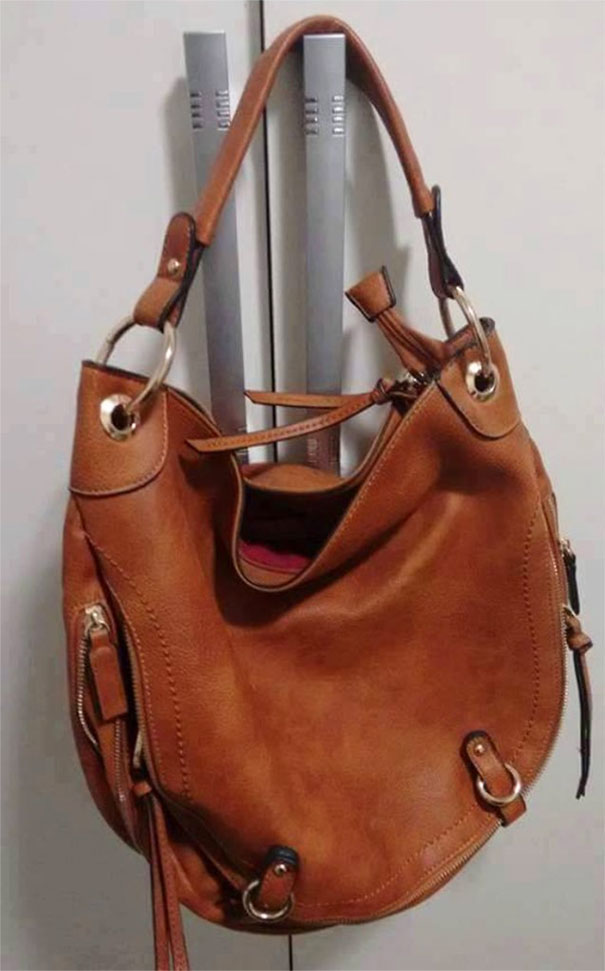 Brown handbag hanging on cabinet handles resembling a smiling face, a funny example of pareidolia in everyday objects