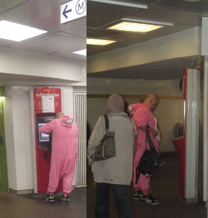 Person in a pink onesie using a red information kiosk in a public area, seemingly indifferent to surroundings.