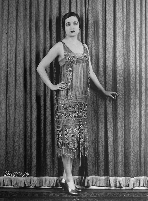 Black and white photo of a 1920s woman in a beaded dress illustrating the perfect female body shape changed over 100 years.