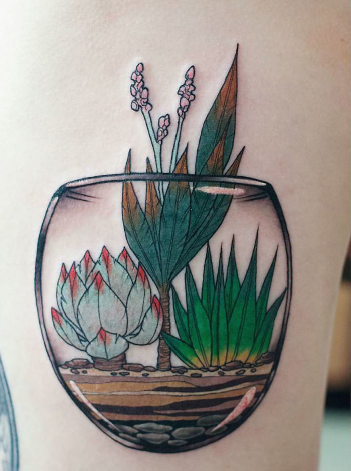 Succulent tattoo of various plants in a glass terrarium, showcasing intricate details and vibrant colors.