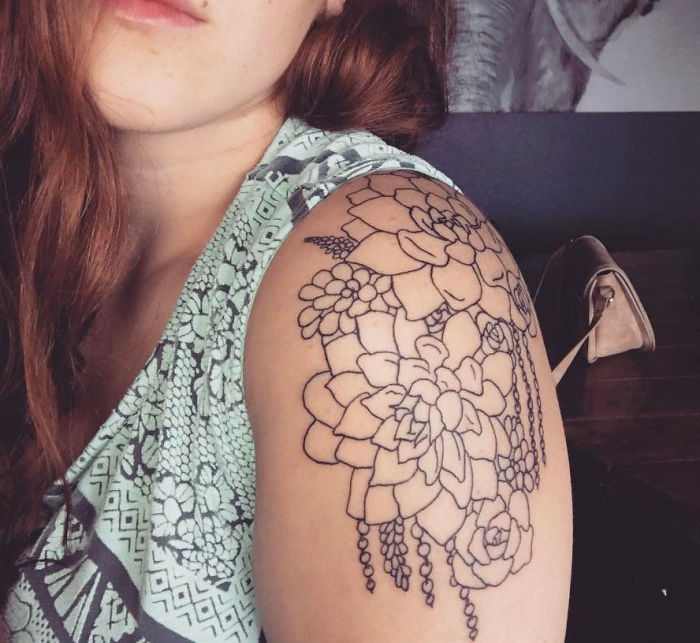 Woman with a detailed succulent tattoo on her upper arm.