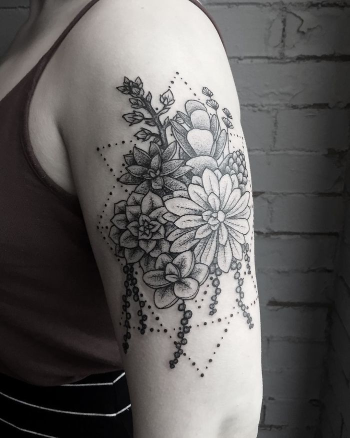 Succulent tattoo design featuring detailed black and white flowers on an upper arm.