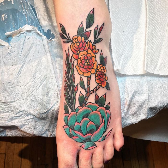 Colorful succulent tattoo on foot featuring green and orange floral designs.