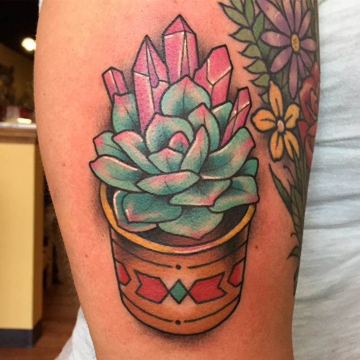 Colorful succulent tattoo with crystals on a person's arm, showcasing vibrant design in a decorative pot.