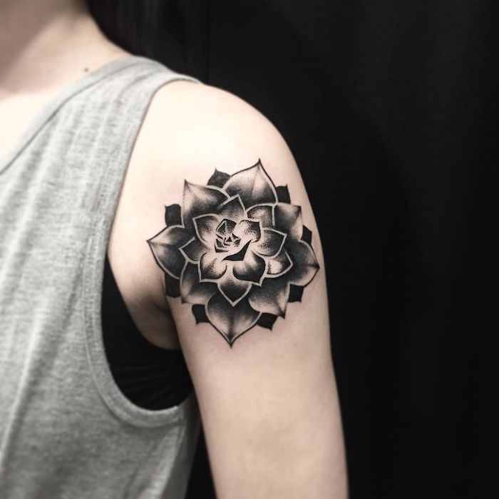 Succulent tattoo in black ink on upper arm, featuring a detailed geometric flower design.