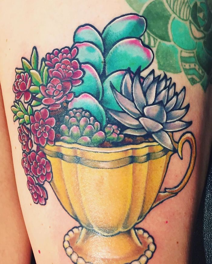 Colorful succulent tattoo featuring various plants in a golden teacup.