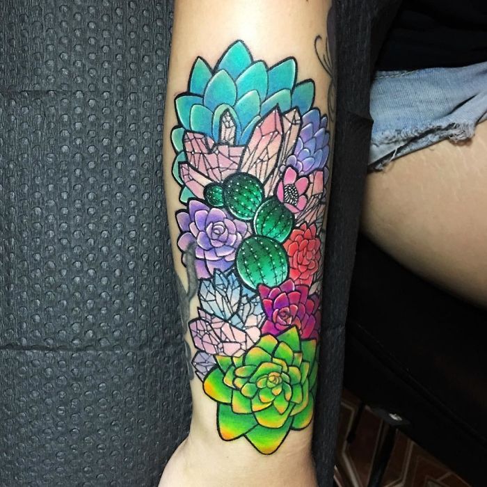 Colorful succulent tattoo on forearm featuring various vibrant succulent designs.