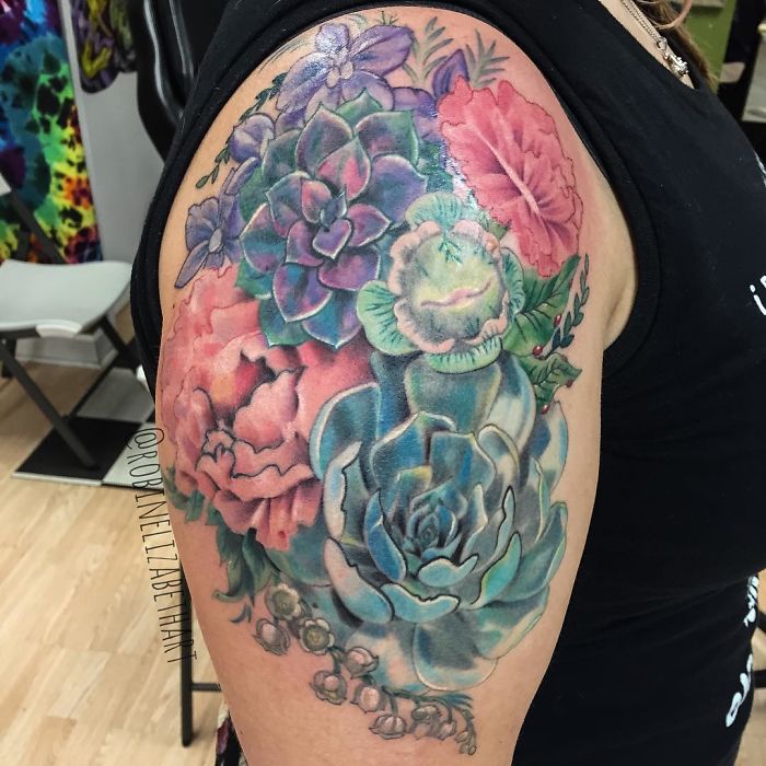 Colorful succulent tattoo on an arm, featuring vibrant flowers and diverse succulent designs.