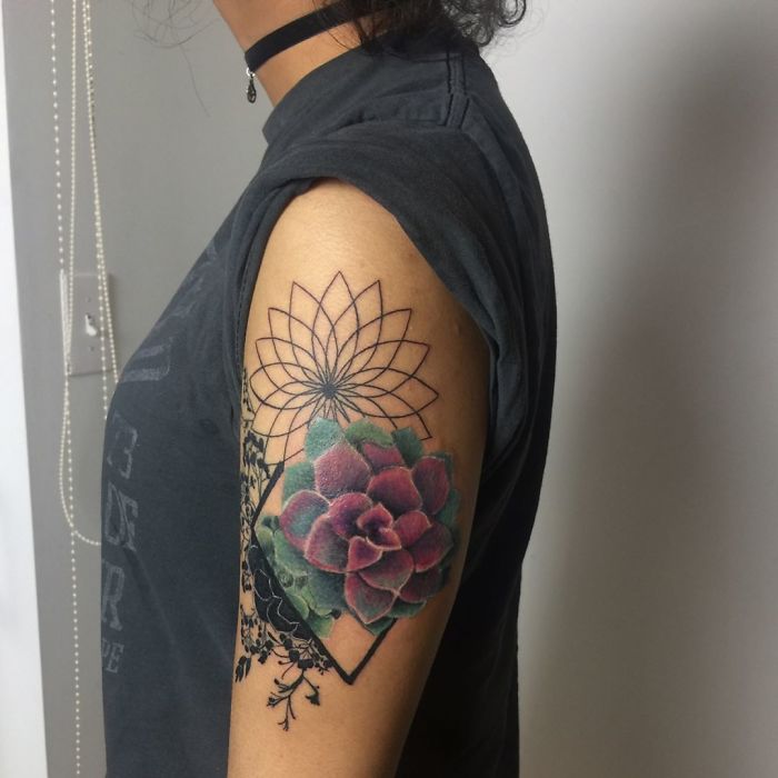 A colorful succulent tattoo on an upper arm with geometric and floral patterns.