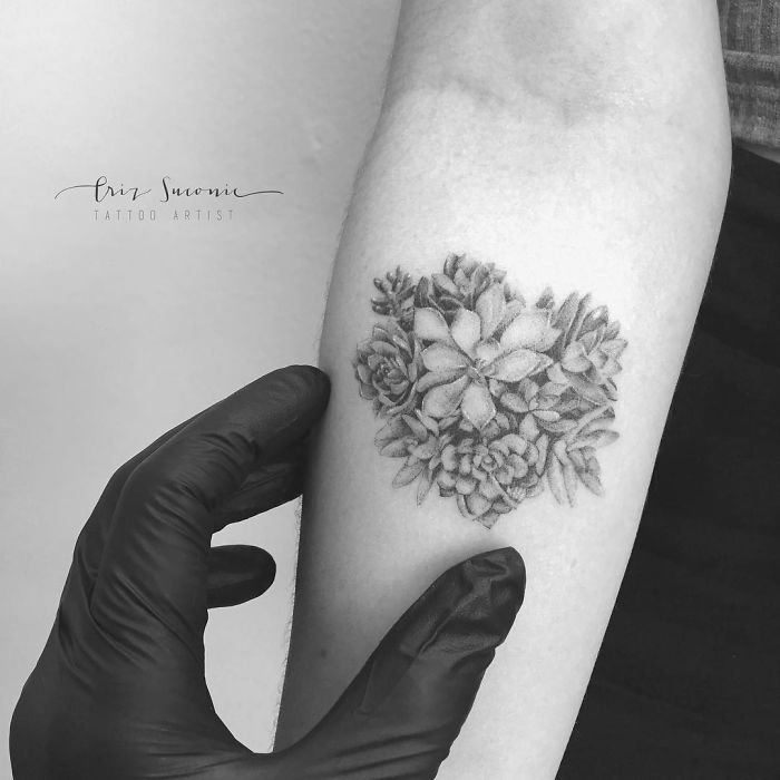 Black and white succulent tattoo on arm held by a person wearing black gloves.
