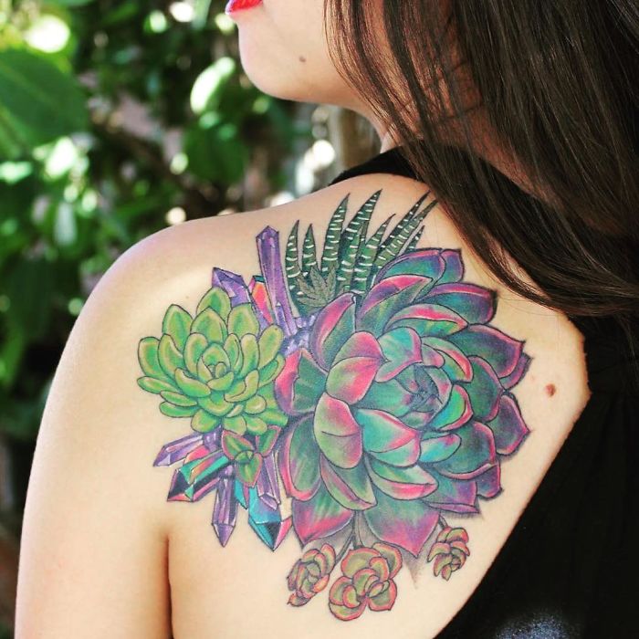 Colorful succulent tattoo on a woman's shoulder, featuring various vibrant succulents and geometric accents.
