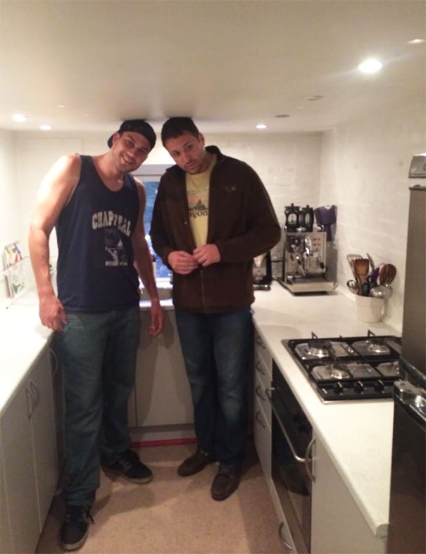 Two tall people struggling to fit in a kitchen with a low ceiling, highlighting everyday tall people struggles humorously.