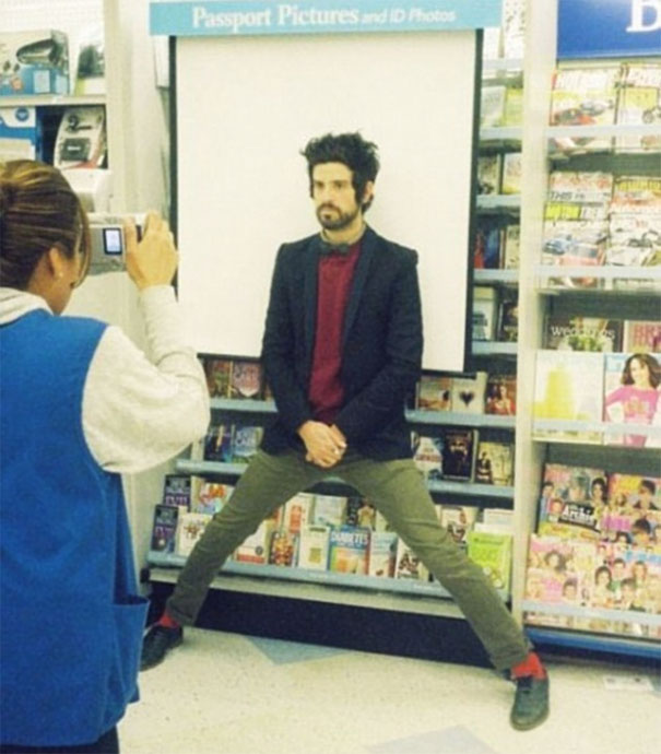 Tall person struggles to fit in passport photo booth, spreading legs wide in a humorous everyday situation.