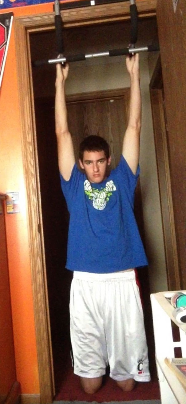 Tall person hanging on a pull-up bar that fits perfectly in a door frame, showing an everyday struggle with ceiling height.