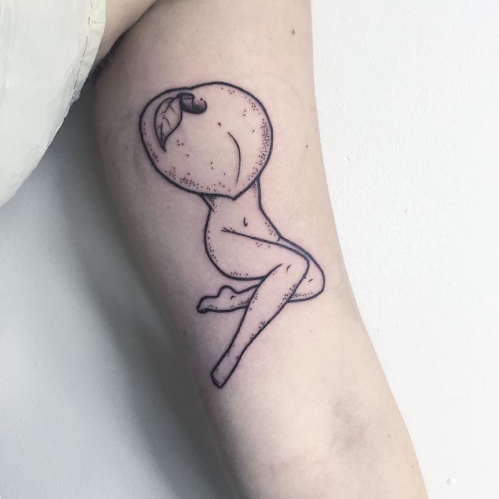 Tattoo of a headless girl with a peach head on an arm, showcasing strangely beautiful art by Molly Jean.