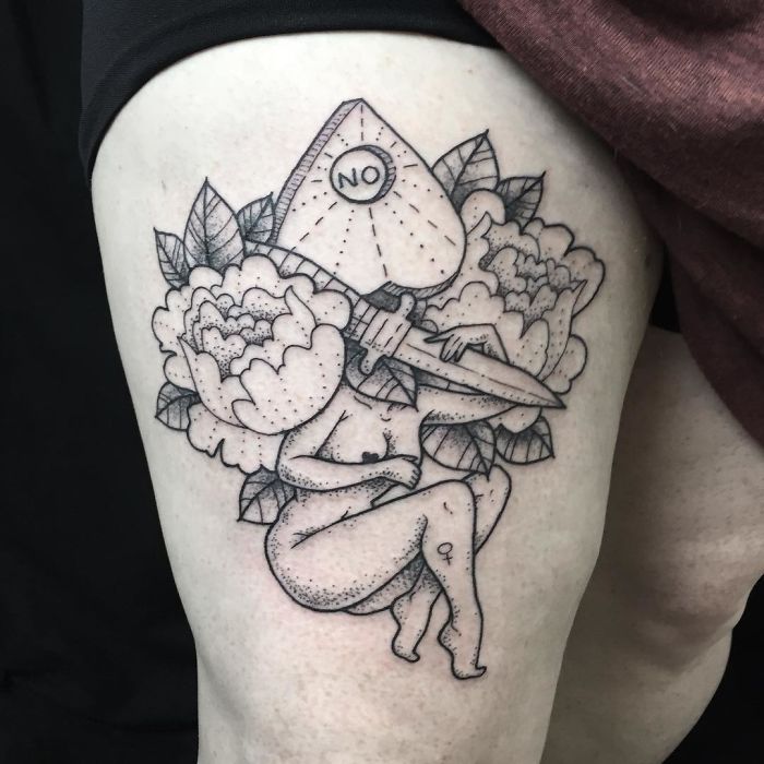 Tattoo of a headless girl with a planchette and floral elements on a thigh.
