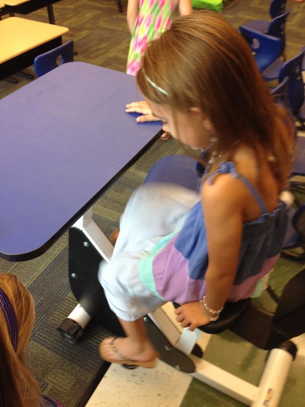 Child using a bicycle desk at school, combining exercise and study for a genius school idea.