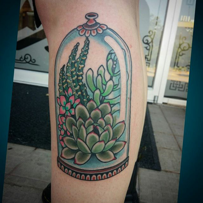 Colorful succulent tattoo design on leg, featuring vibrant plants enclosed in a glass dome.