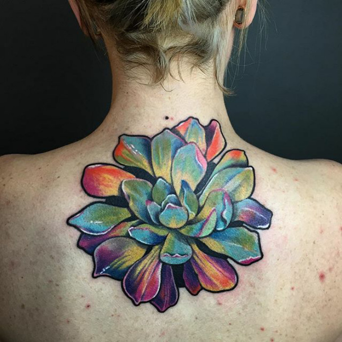 Colorful succulent tattoo on upper back, featuring vibrant hues and intricate details.