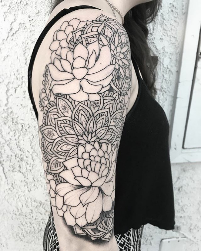 Black and white succulent tattoo design on a woman's upper arm, featuring intricate floral patterns.
