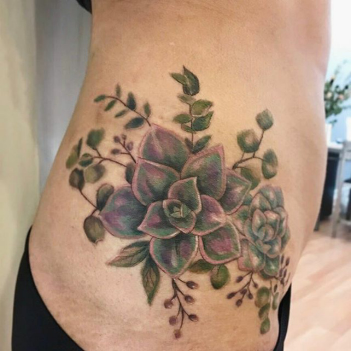 Succulent tattoo on a person's side featuring colorful leaves and branches, showcasing a creative body art design.