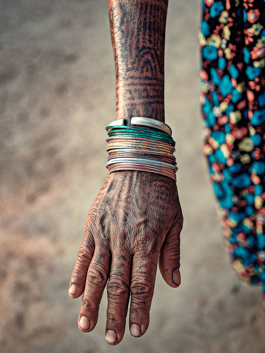Tattooed hand of a Tharu woman adorned with colorful bangles.
