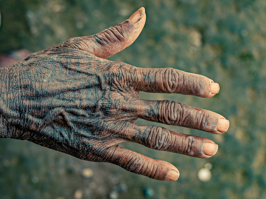 A tattooed hand of a Tharu tribe woman, showing intricate traditional designs and aged skin.