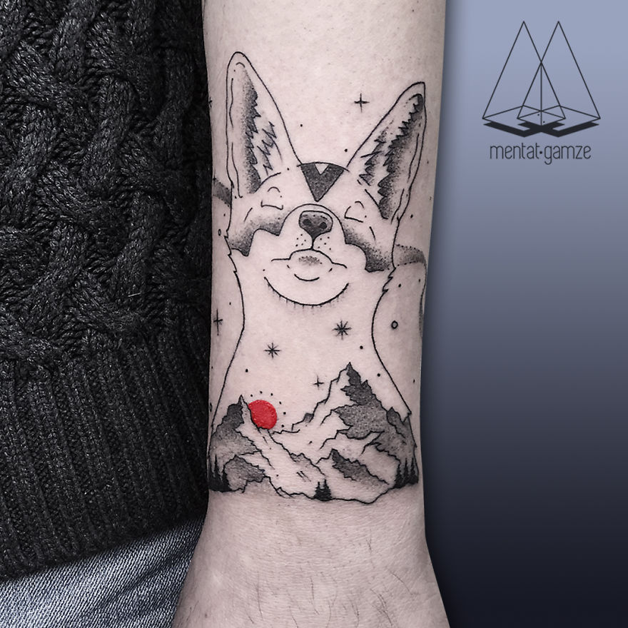 Tattoo of a fox and mountains with a red dot, showcasing intricate design and skilled artistry on a forearm.