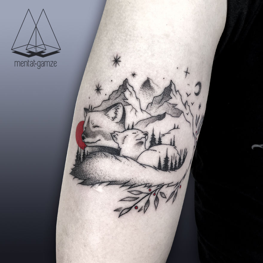 Tattoo on an arm featuring mountain scenery, stars, a red dot, and two foxes.