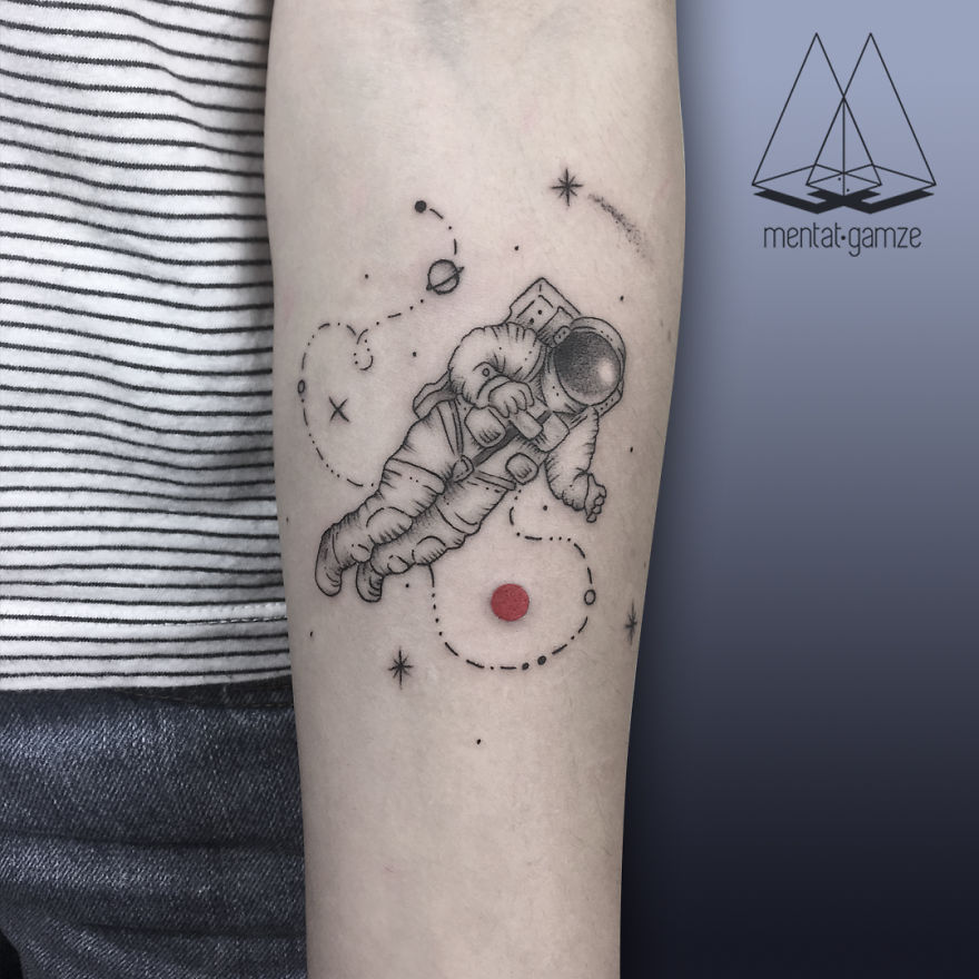 Tattoo of an astronaut floating near a red dot on a person's arm, showcasing unique tattoo artistry.