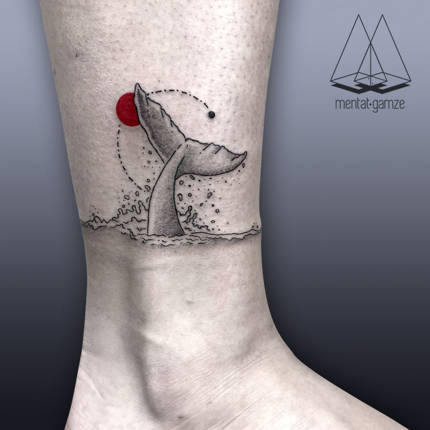 Tattoo of a whale tail with a red dot and geometric elements on a person's leg.