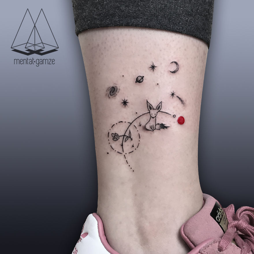 Tattoo art with a fox and planets, featuring a red dot, on an ankle above pink sneakers.