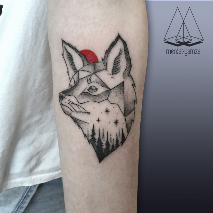 Geometric fox tattoo with a red dot and forest design on the arm, showcasing creative tattoo artistry.
