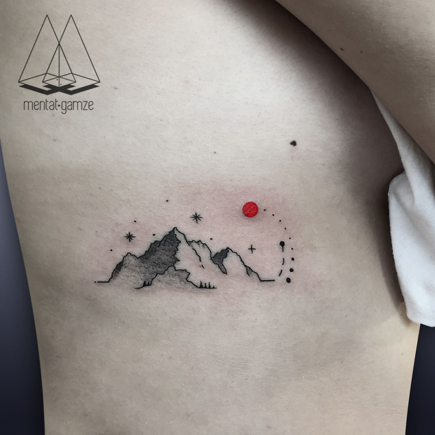 Tattoo of mountains and stars with a prominent red dot on skin, showcasing a new artist's work.