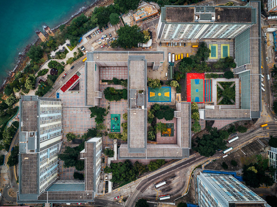 Aerial view of claustrophobic living spaces in Hong Kong, showing tightly packed residential buildings and small outdoor courts.
