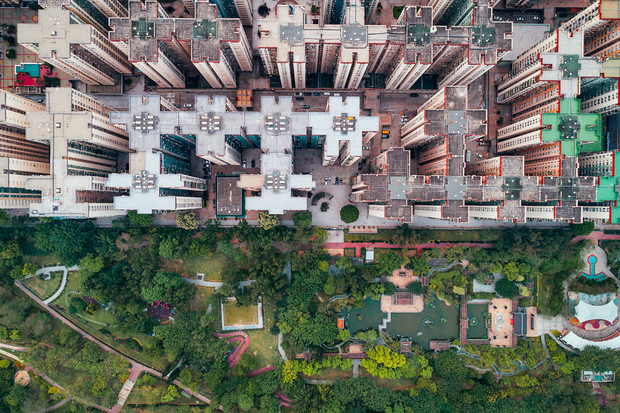 Aerial view of claustrophobic living spaces in Hong Kong with densely packed high-rise buildings above green park areas.