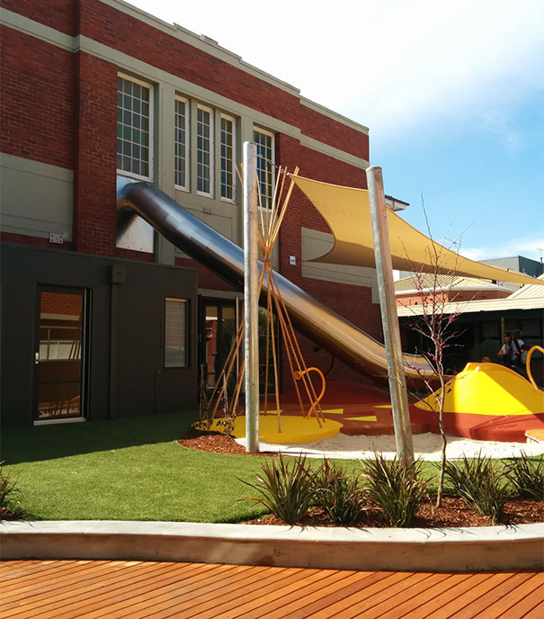 Innovative school playground with a slide exiting a building, featuring modern design elements.