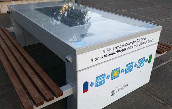 Solar-powered charging station in a school setting with benches, providing free device recharging for students.