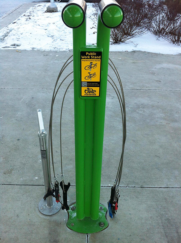 Public bike repair stand with tools, showcasing a practical school idea with green design on a snowy pathway.