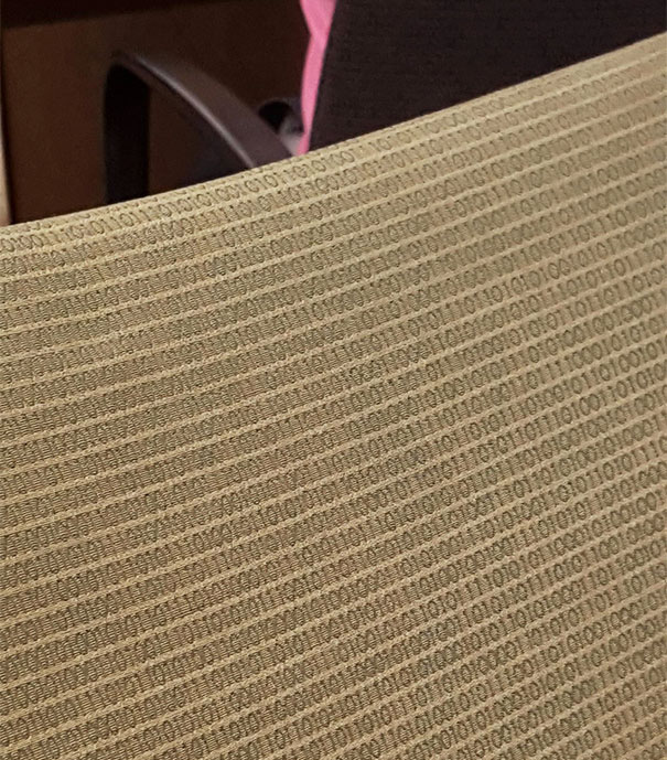 Close-up of a chair fabric patterned with binary codes, representing genius school ideas in creative design.