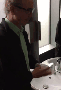 Person using hand dryer with water dripping back into sink, illustrating one of the funniest design fails.