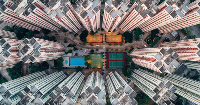 Aerial view of claustrophobic living spaces in Hong Kong with dense high-rise residential buildings and small recreational areas.