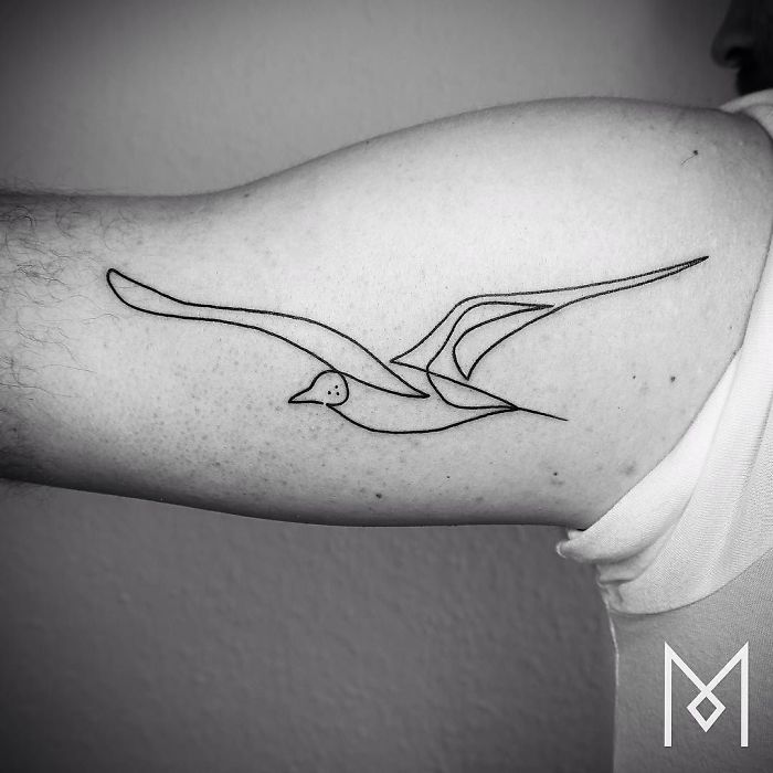 Single continuous line tattoo of a bird on arm by Mo Ganji.