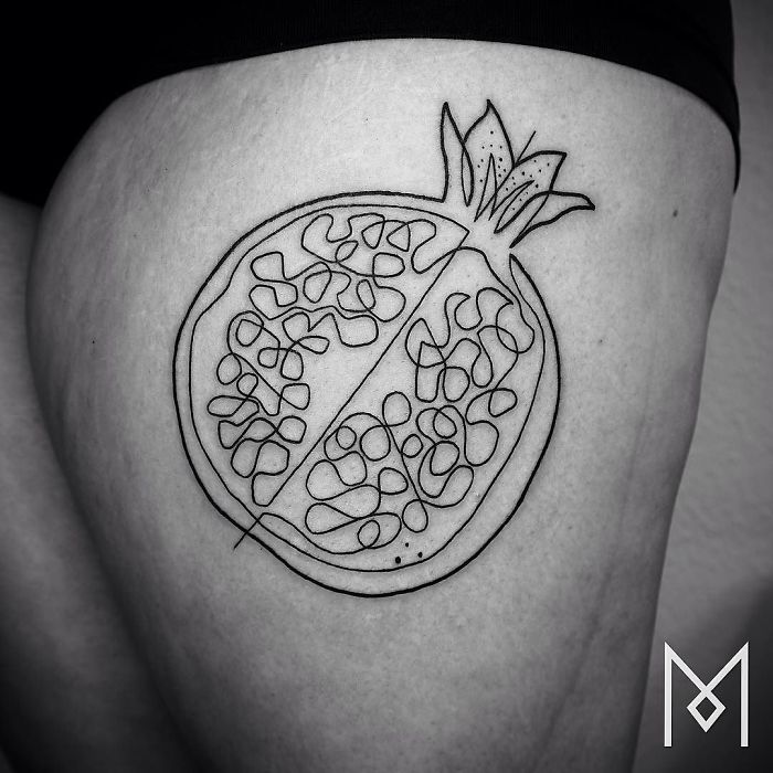 Single-line pomegranate tattoo by Mo Ganji on skin, showcasing intricate continuous design.
