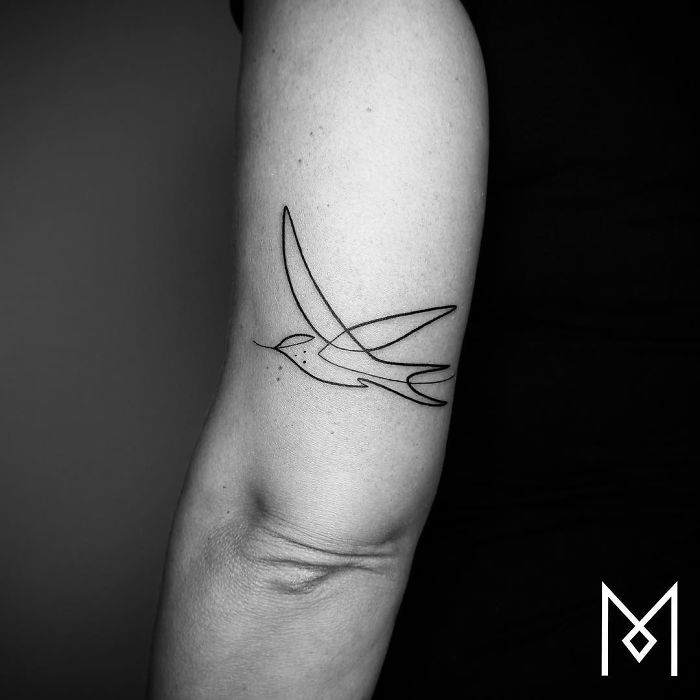 Single continuous line tattoo of a bird on an arm by Mo Ganji.