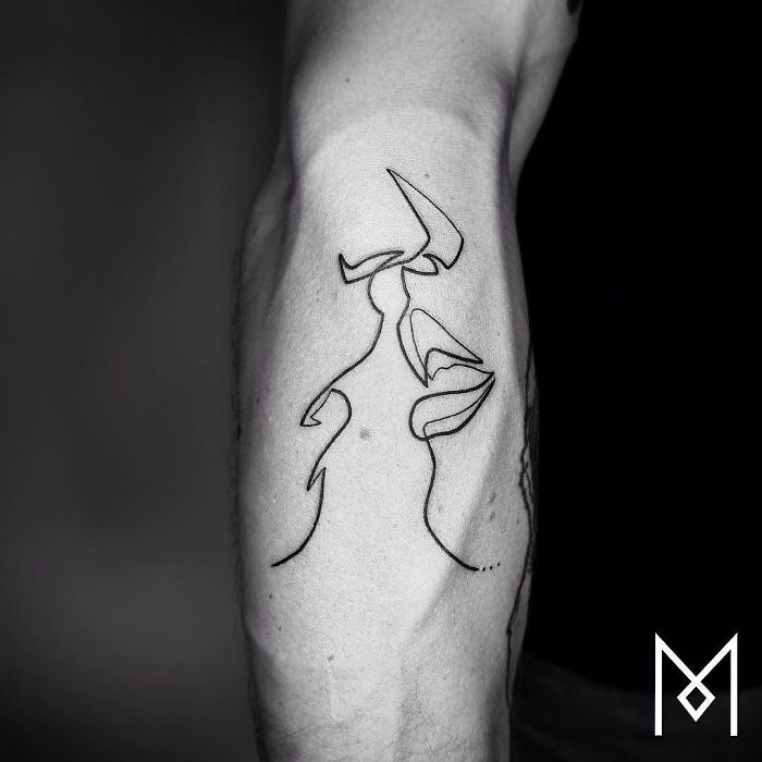 A single continuous line tattoo by Mo Ganji, depicting two faces on an arm.