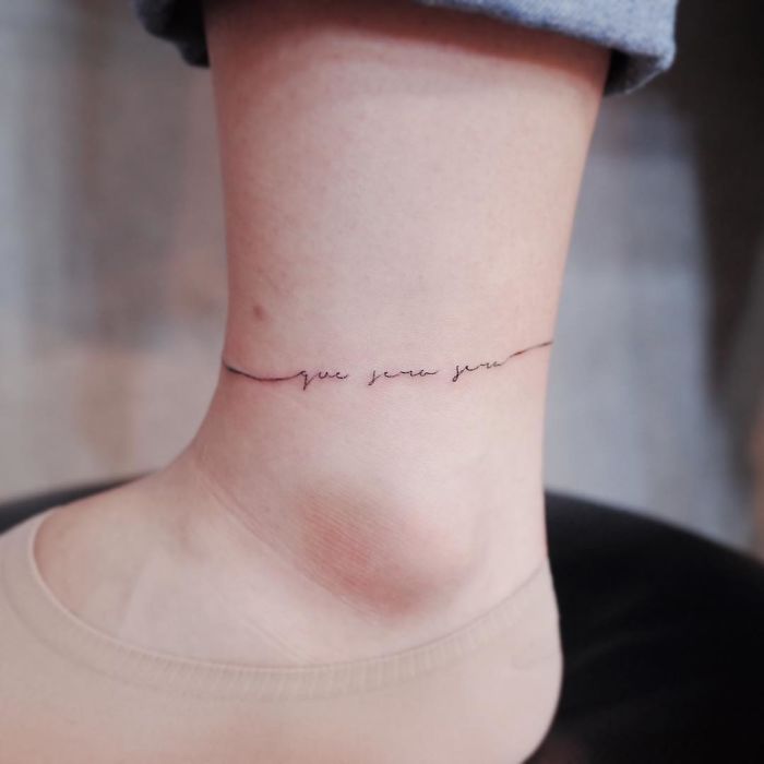 Minimalist tattoo on ankle with delicate scripted line, showcasing discreet and tiny design.
