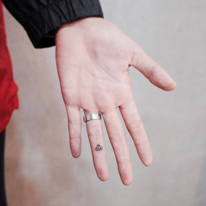 A discreet, minimalistic tattoo of a triangle on a person's finger, showcasing tiny minimalist body art.